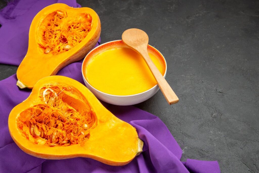 Front view of simple pumpkin soup on purple tissue and dark table