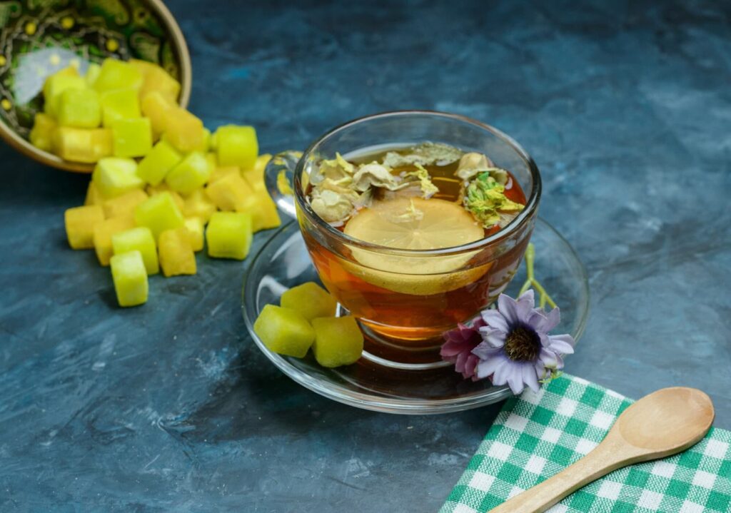 Herbal lemony tea with sugar cubes, spoon and tea towel