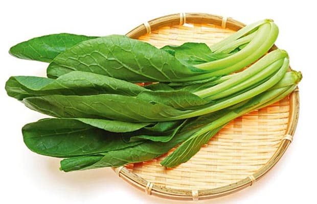 The green salad leaves lay on a wooden plate