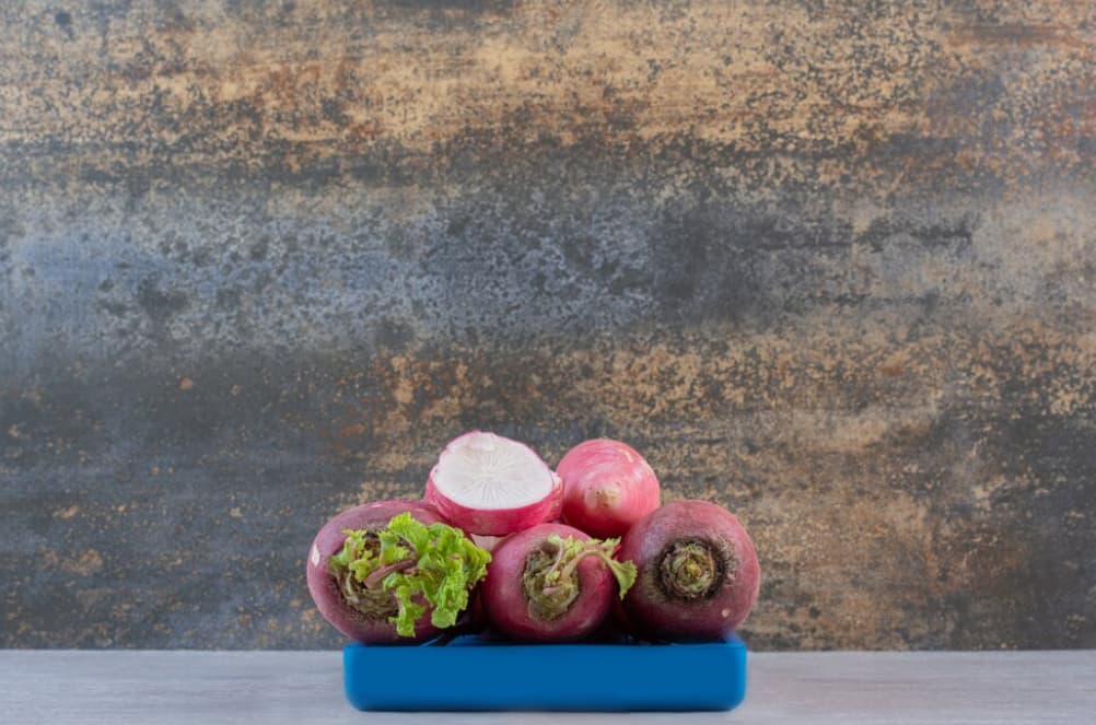 Sliced and whole turnips on a cutting board with a rustic backdrop.