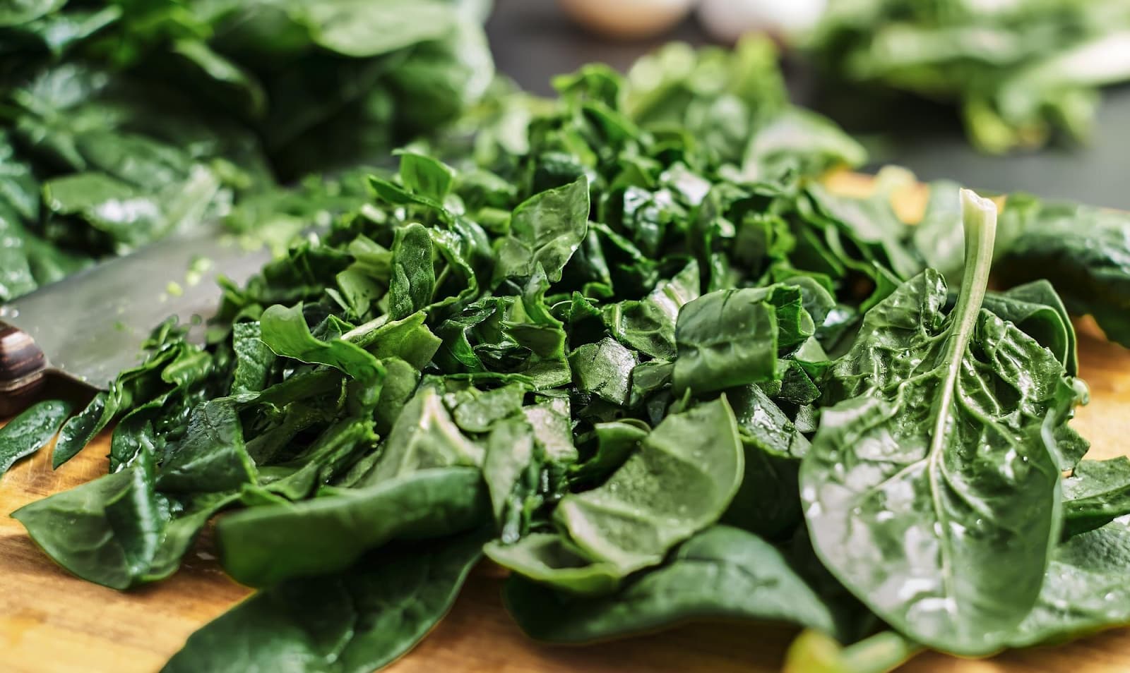 Green chopped leaves lie on a wooden cutting board