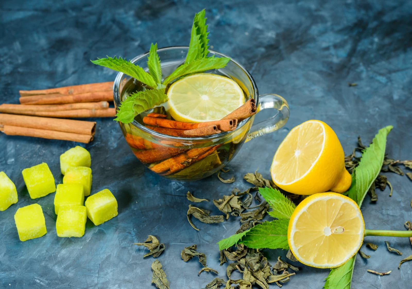 Tea in a cup with lemon, mint, cinnamon sticks, sugar cubes