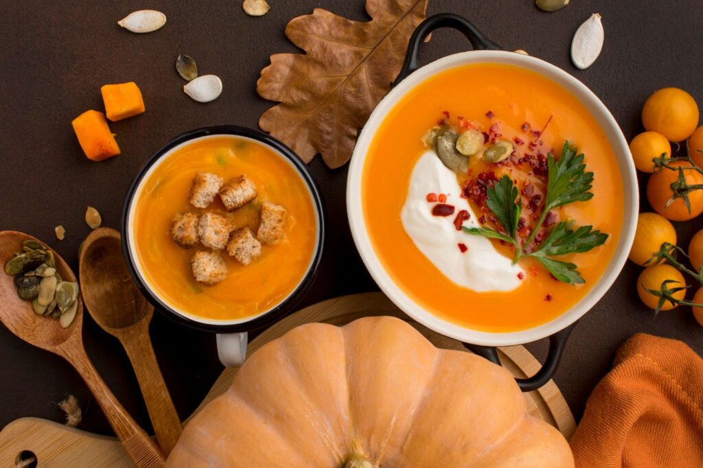 Top view of winter squash soup in bowl and mug with croutons and parsley