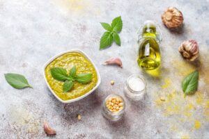 Top view of italian basil pesto sauce with culinary ingredients for cooking