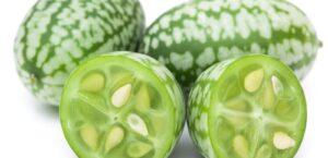 Green and white striped fruits sliced open, revealing seeds.