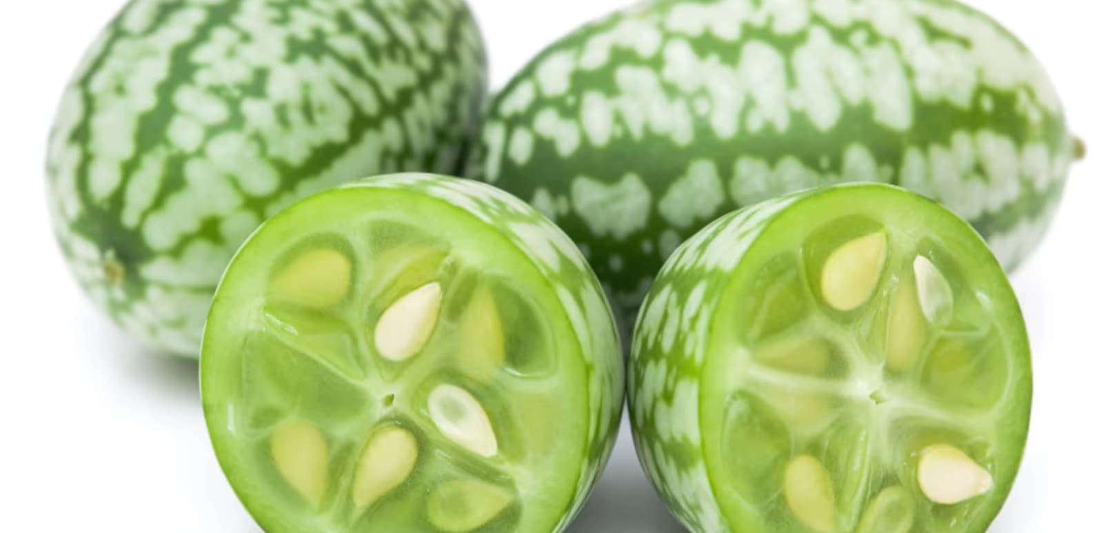 Green and white striped fruits sliced open, revealing seeds.