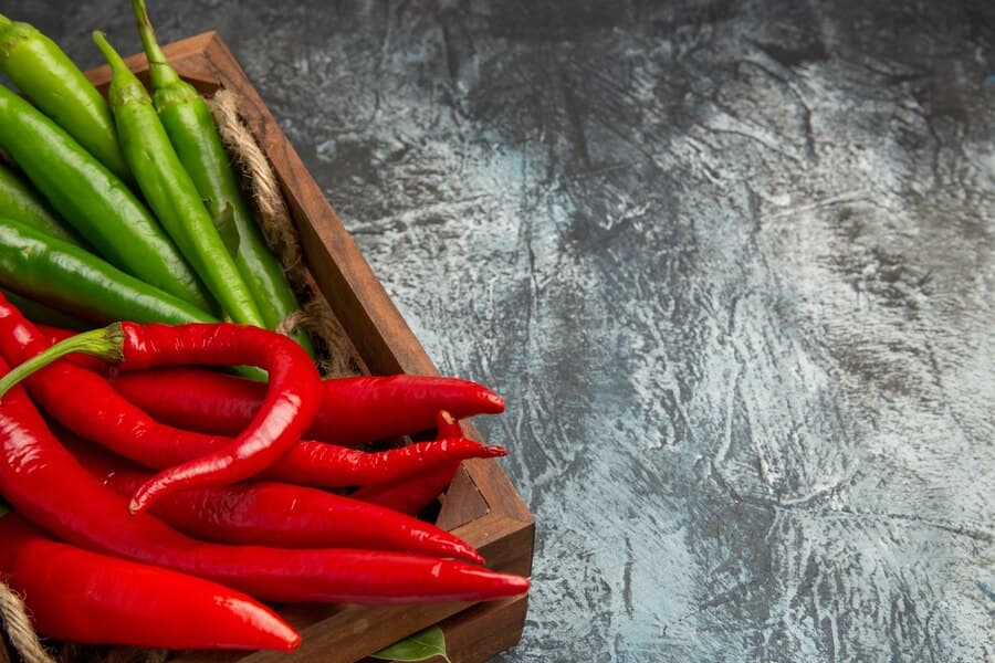 Red and green fresh peppers are in the basket 