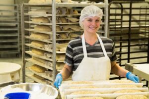 A girl holds a tray of fresh bread at the factory