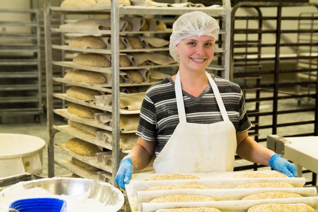 A girl holds a tray of fresh bread at the factory